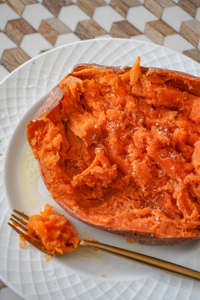 a sliced microwave sweet potato fully opened to reveal the creamy mashed center