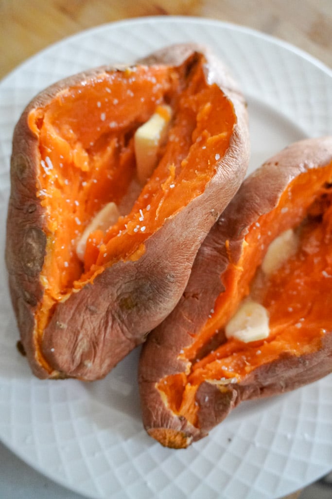two microwave sweet potatoes sliced open with pats butter inside