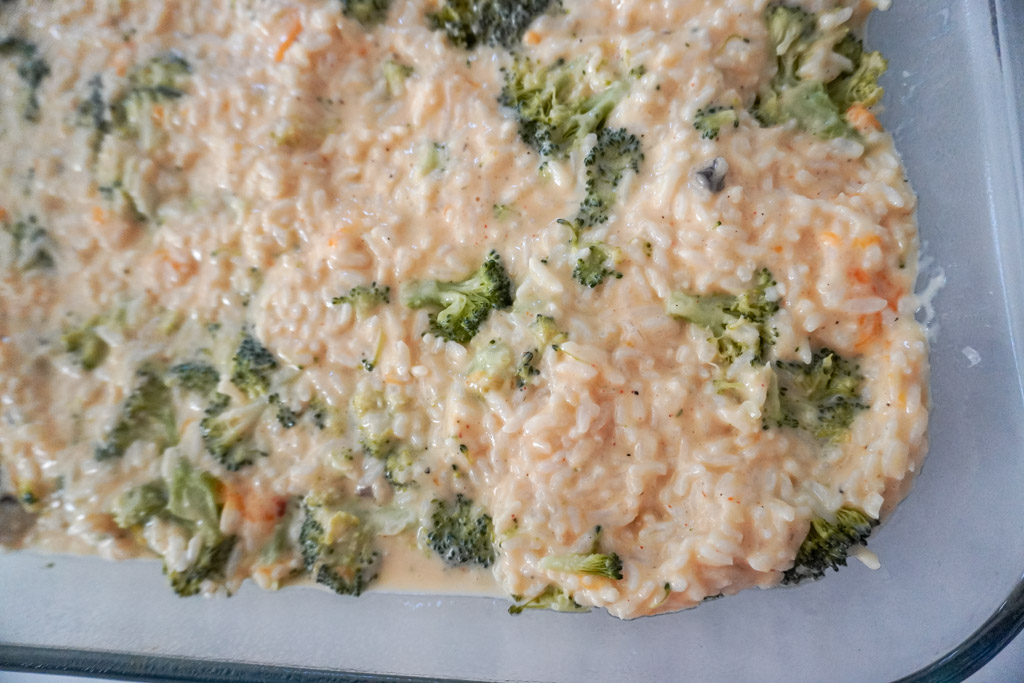 close up view of uncooked cheddar broccoli rice in a casserole dish