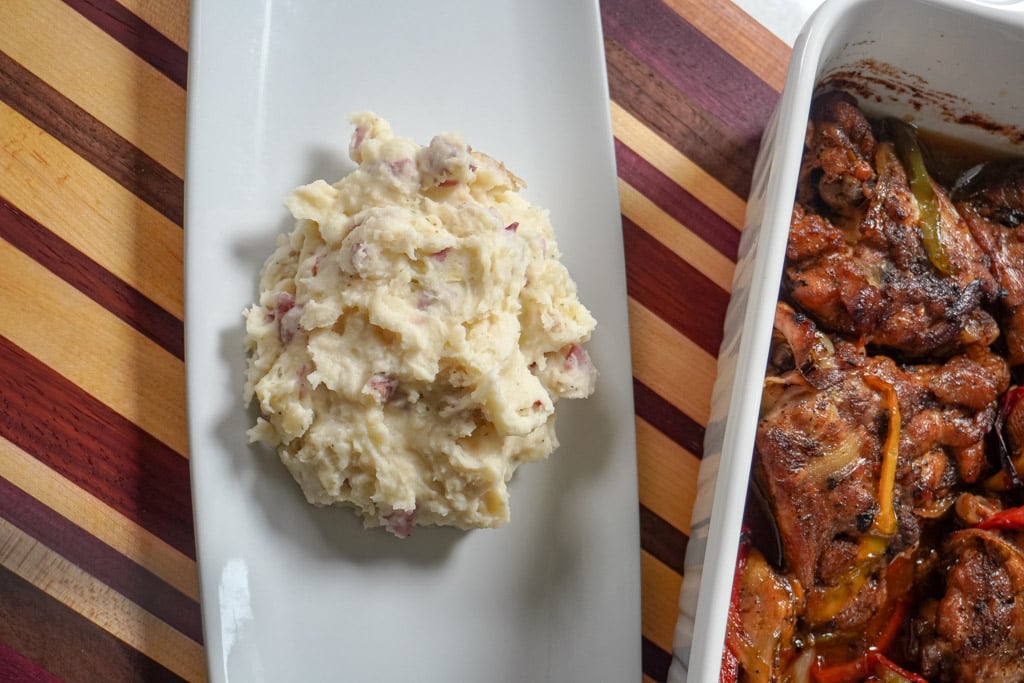 plated mashed red potatoes next to a dish of baked chicken