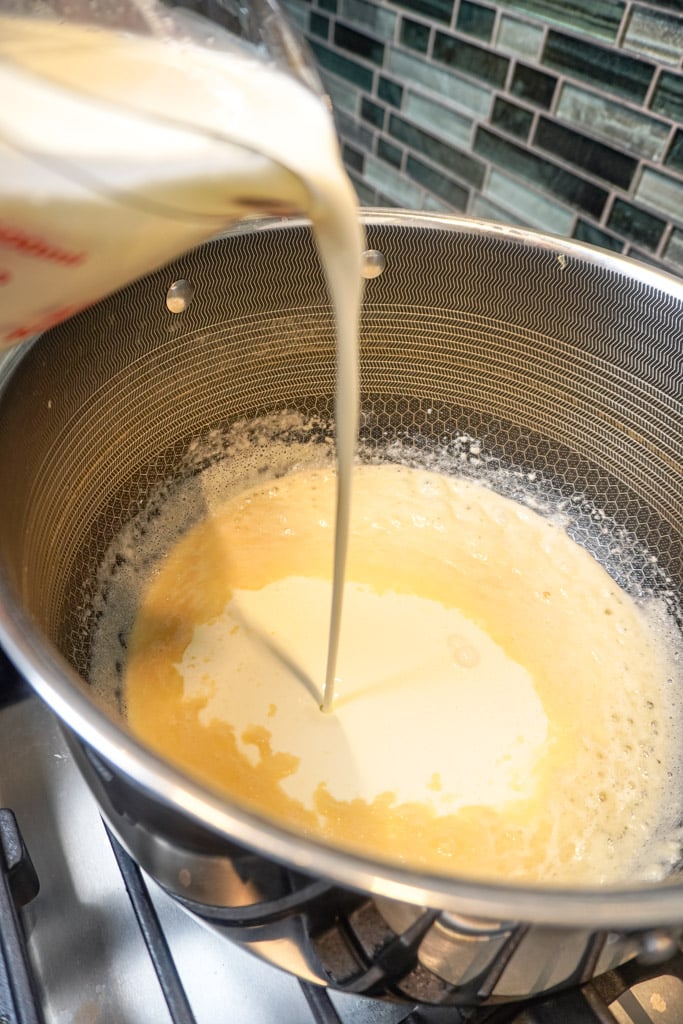 milk being poured from a measuring cup into a pot