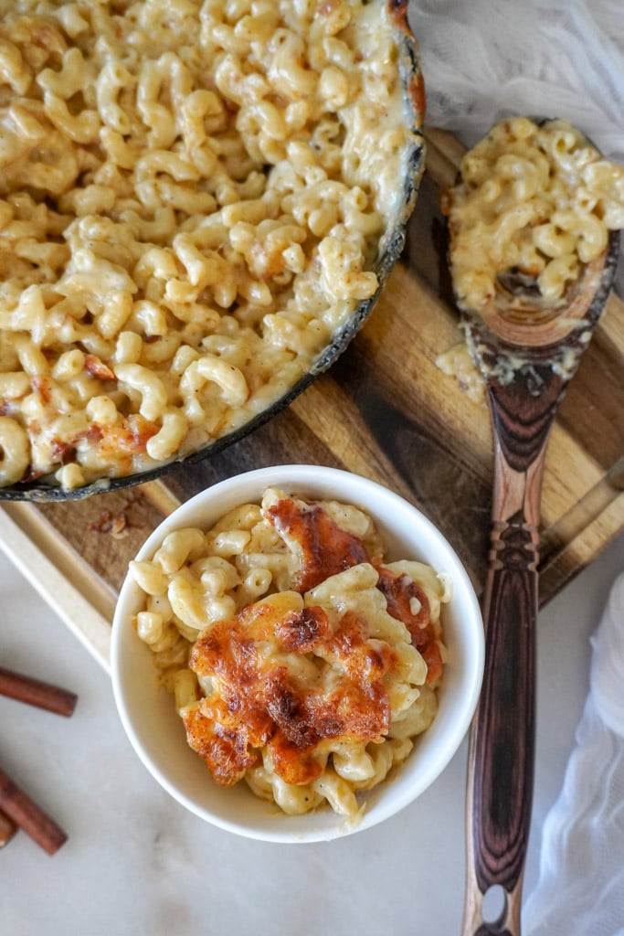 a small bowl of gouda mac and cheese beside a large skillet containing more