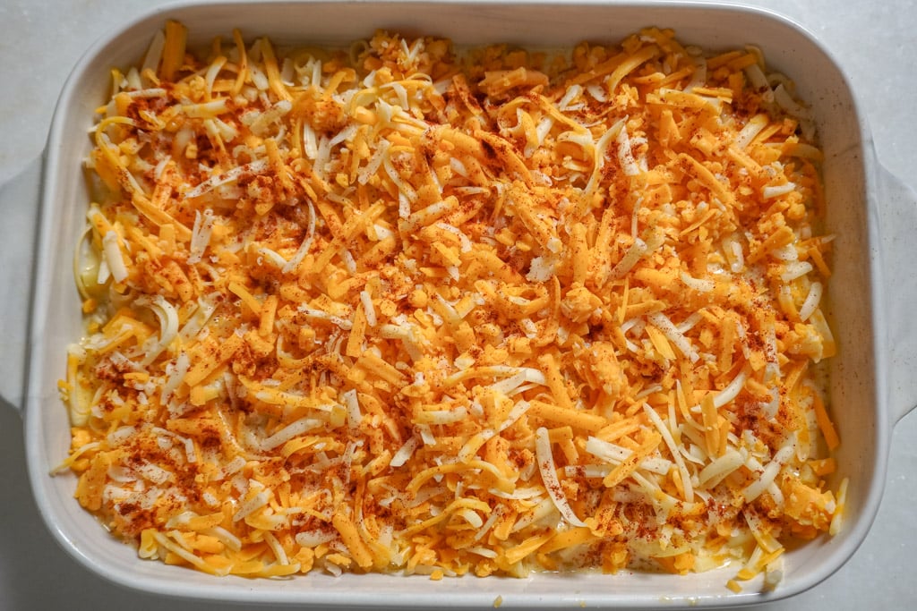 macaroni and cheese being layered in a white baking dish