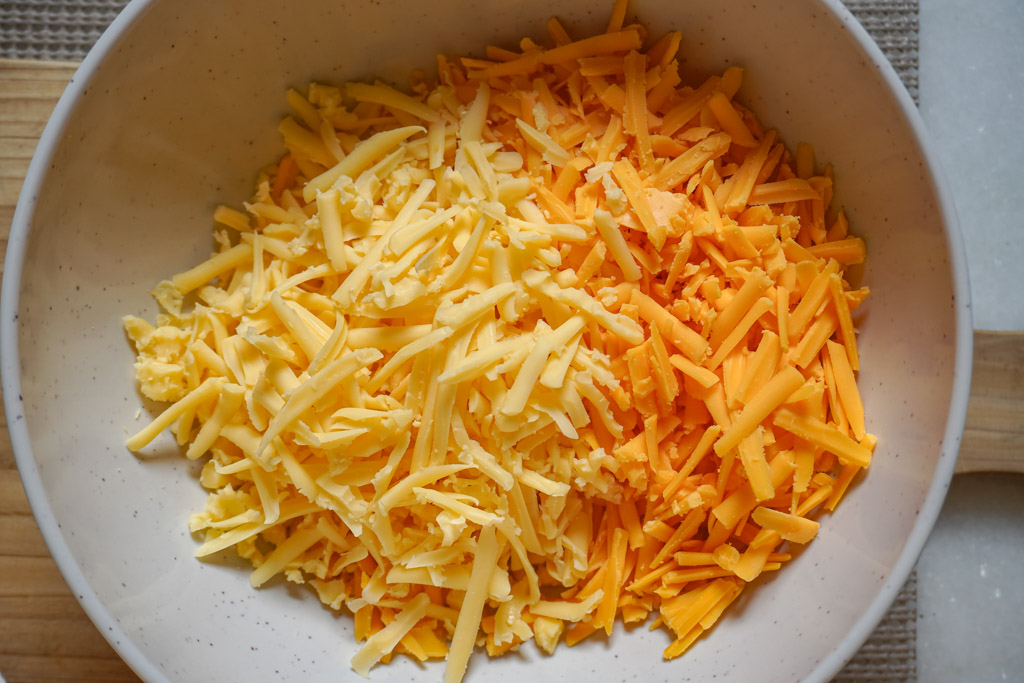 a bowl of grated cheddar cheese