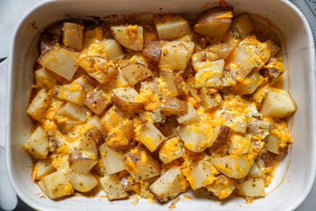 layering potatoes and cheese in a baking dish to make cheesy ranch potatoes