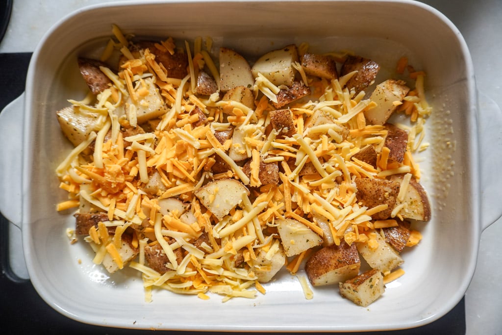layering potatoes and cheese in a baking dish to make cheesy ranch potatoes