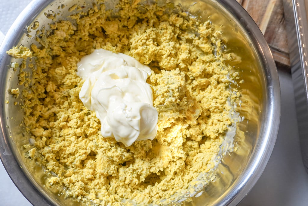 mashed seasoned egg yolks in a bowl with mayo placed on top of the mixture