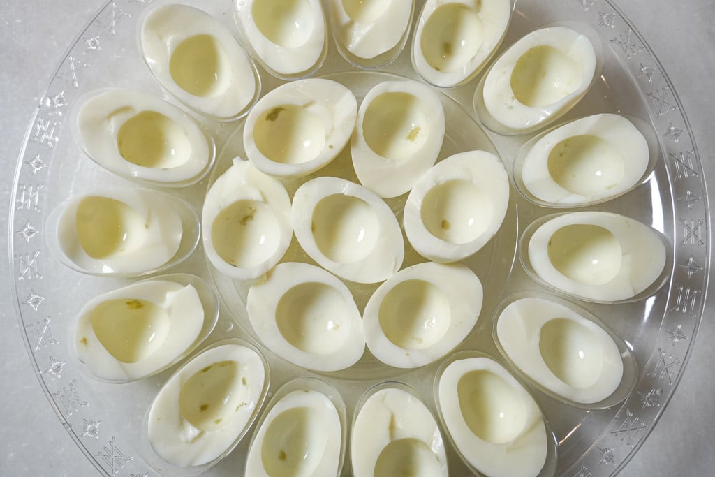 boiled egg whites on a platter, sliced in half with the yolks removed