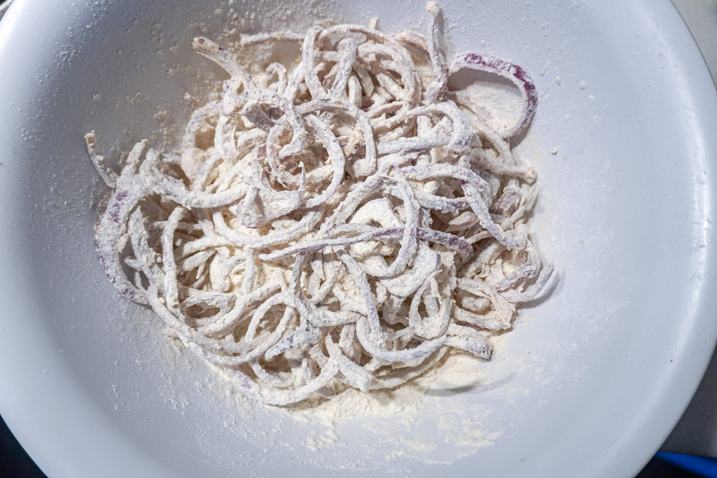 rsw onions rings coated with seasoned flour in a white bowl