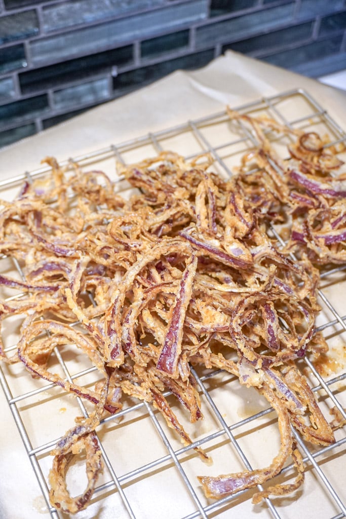 french fried onions draining on a wire rack