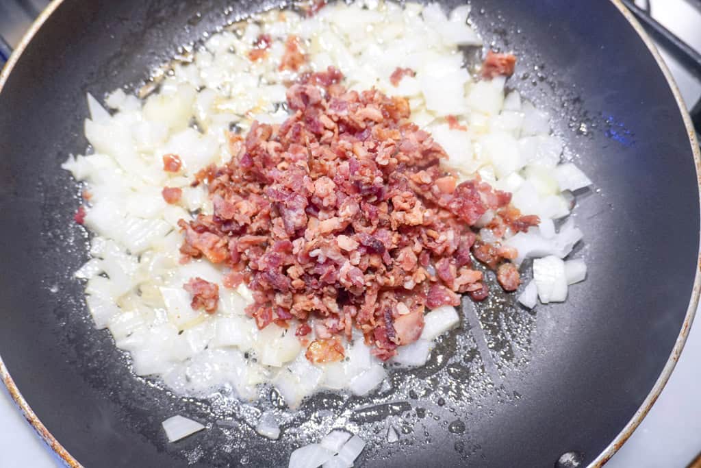 onions sautéing with bacon in a pan