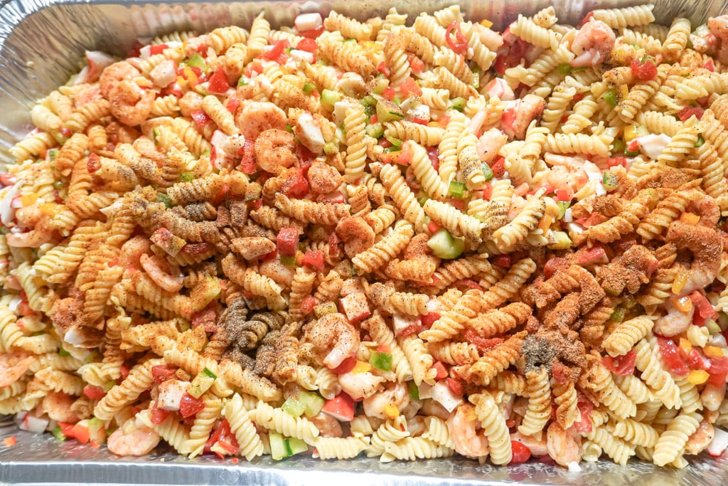 a pan of seafood pasta salad with seasoning sprinkled over it