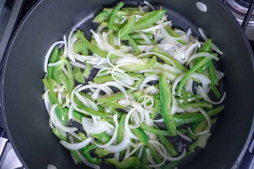 sliced bell peppers and onions sautéing in a pot