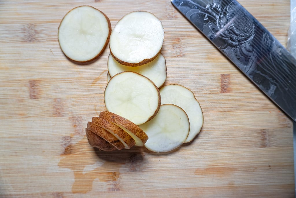 a sliced potato on a cutting board beside a knife