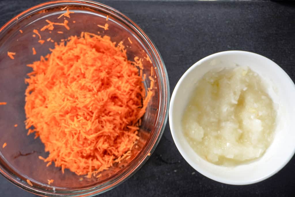 a bowl of shredded carrots beside a smaller bowl of shredded onions