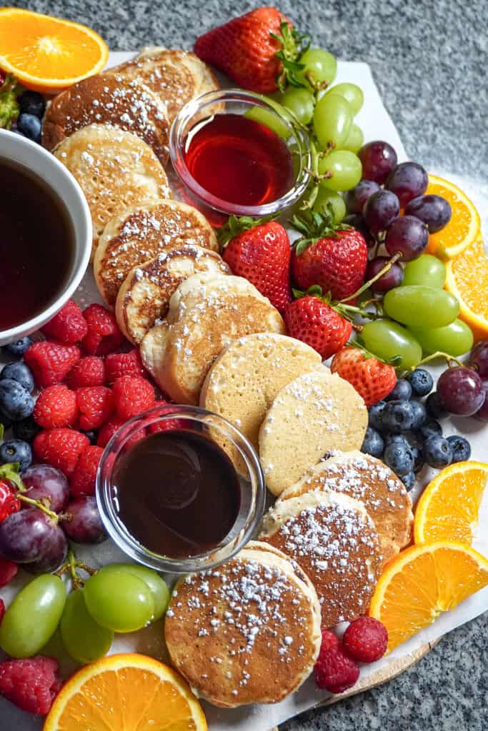 a brunch board with fruits and pancakes