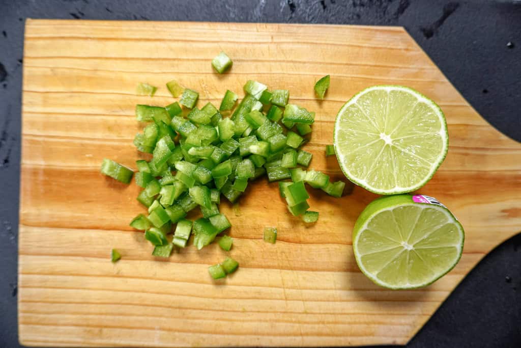 diced peppers and a sliced lime on a cutting board