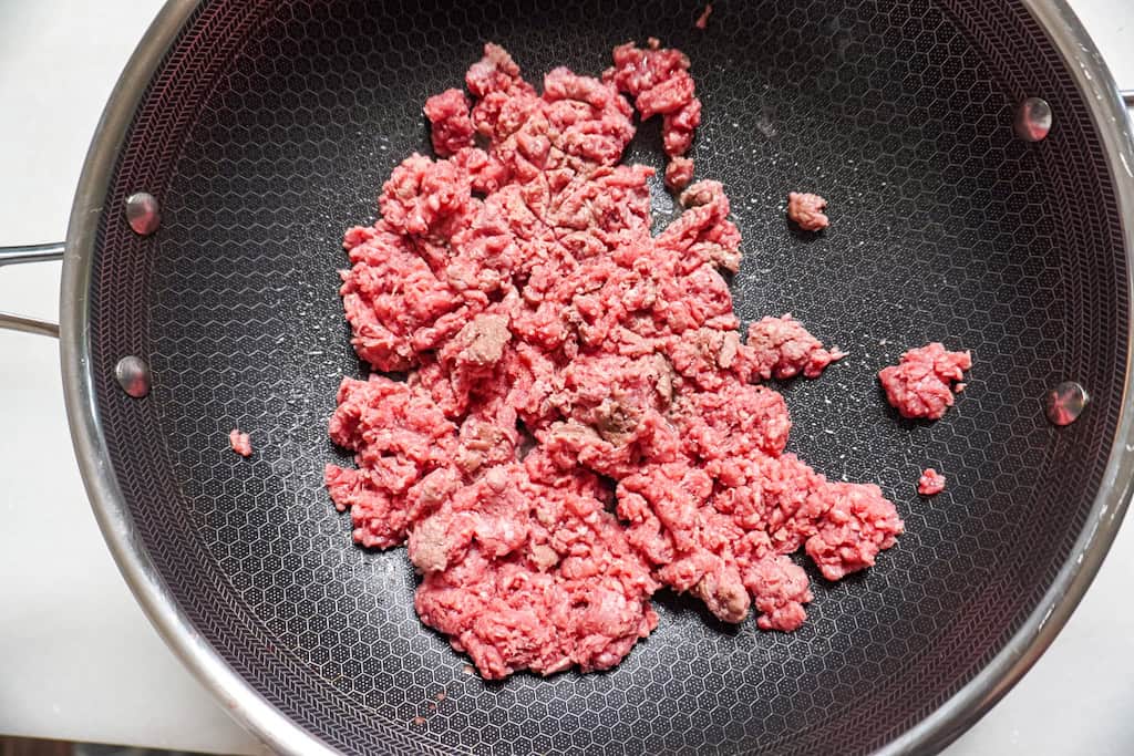 raw ground beef added to skillet