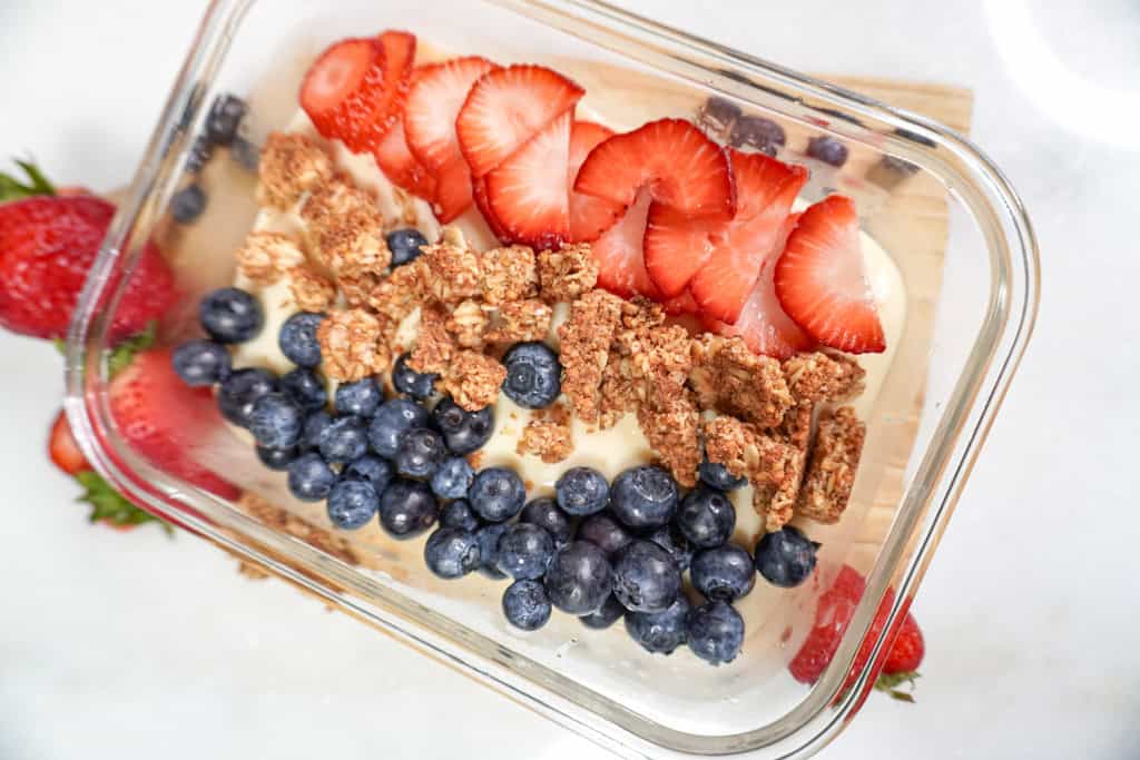 a dish of cheesecake protein pudding topped with berries and granola