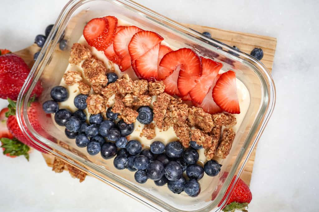 a dish of cheesecake protein pudding topped with berries and granola