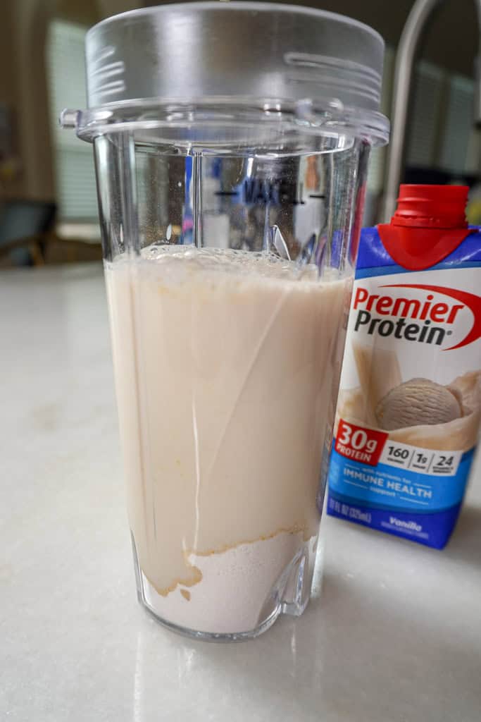 a blender filled with Premier Protein shake and jello mix beside a container