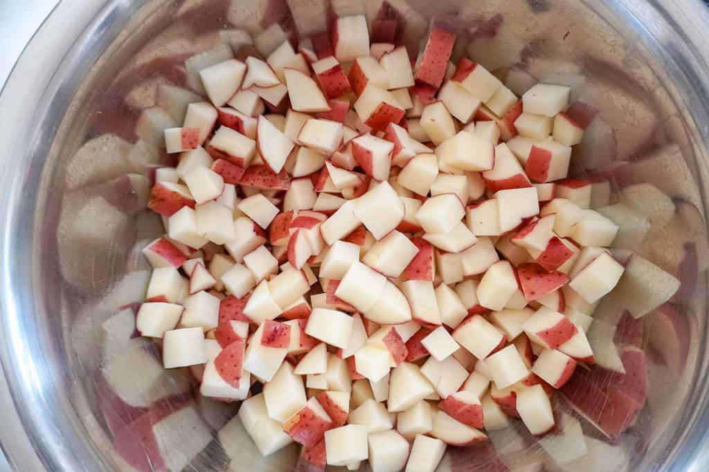 A bowl filled with diced red potatoes ready for cooking.