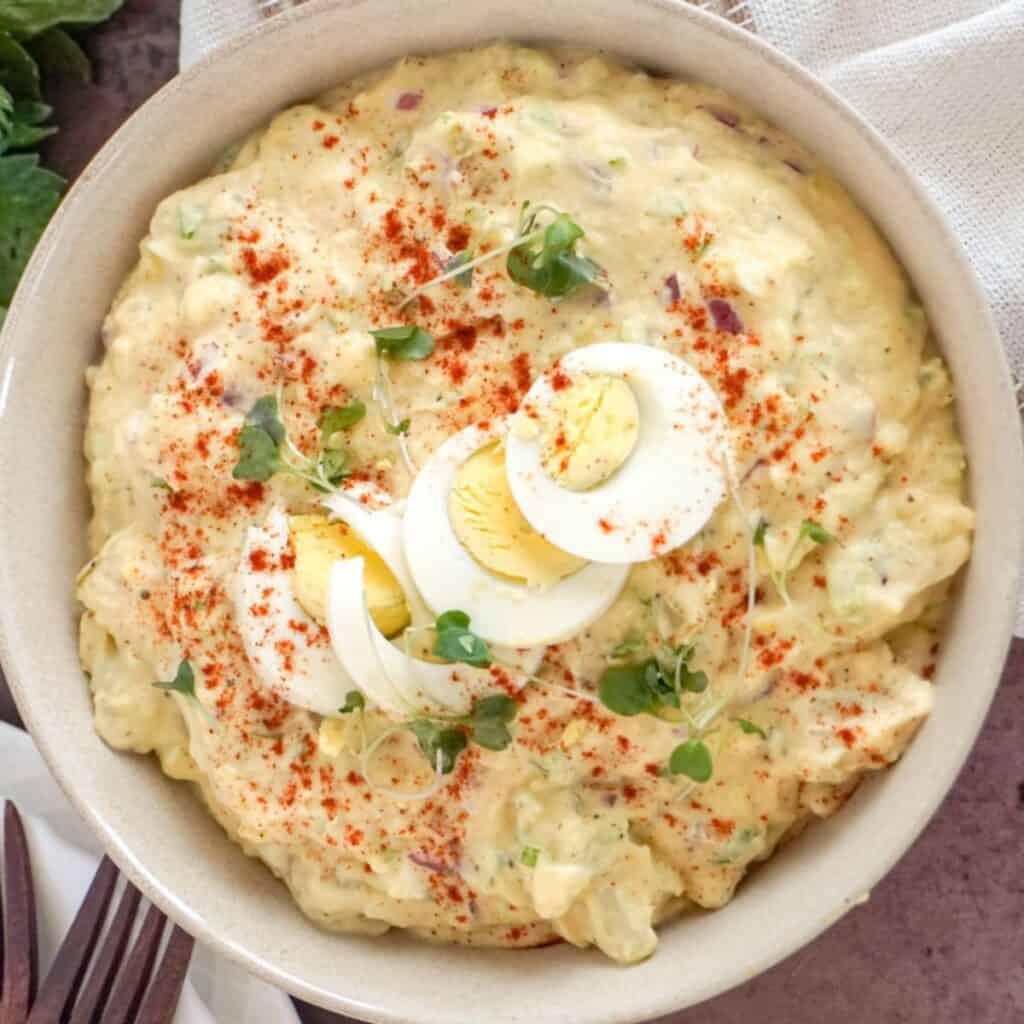 a bowl of southern potato salad garnished with sliced boiled eggs