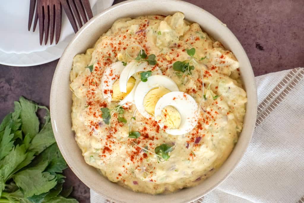 a bowl of southern potato salad garnished with sliced boiled eggs