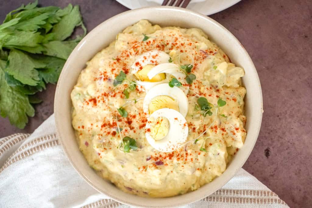 a bowl of southern potato salad garnished with sliced boiled eggs