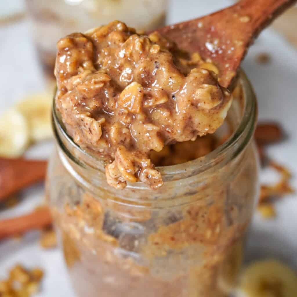 High-protein overnight oats in a jar, topped with banana slices, walnuts, and a drizzle of peanut butter.