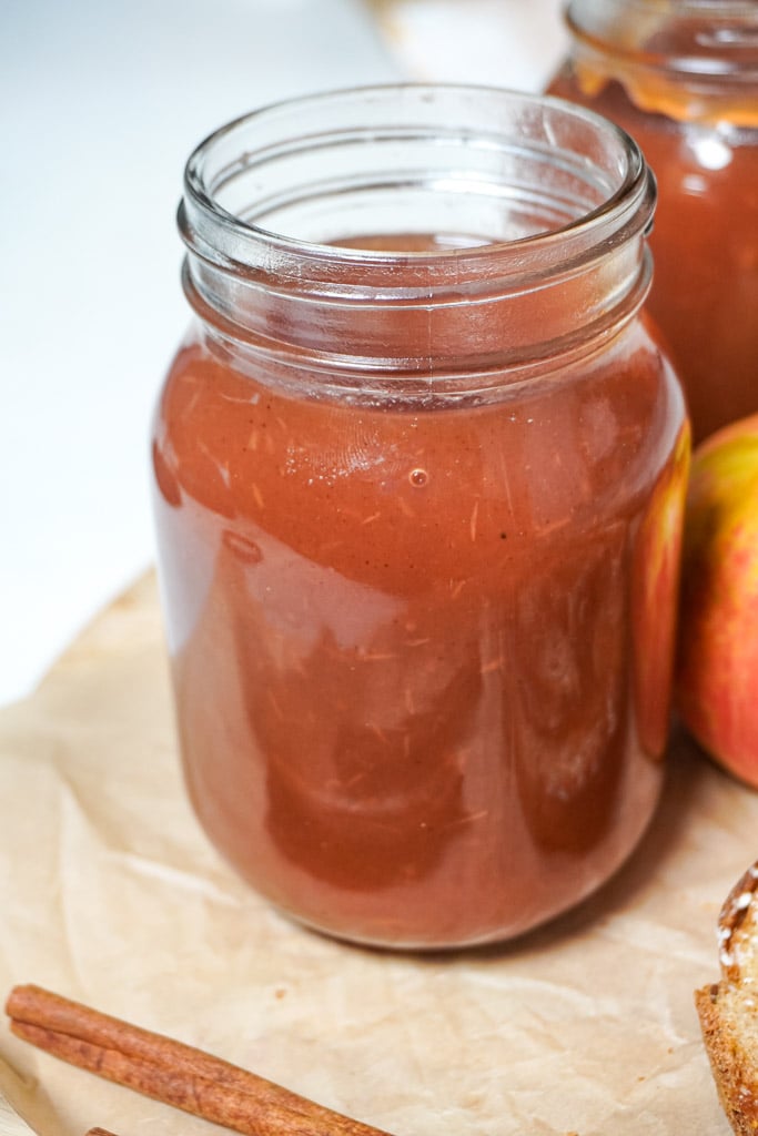 apple butter in a mason jar on a cutting board