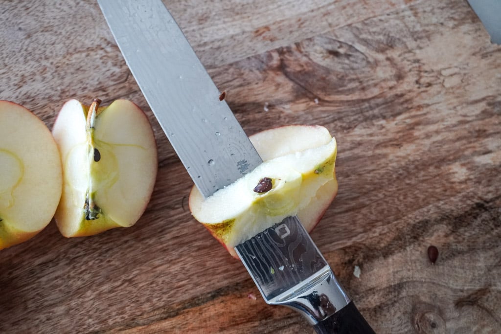 using a knife to remove the seeds and core out of an apple.