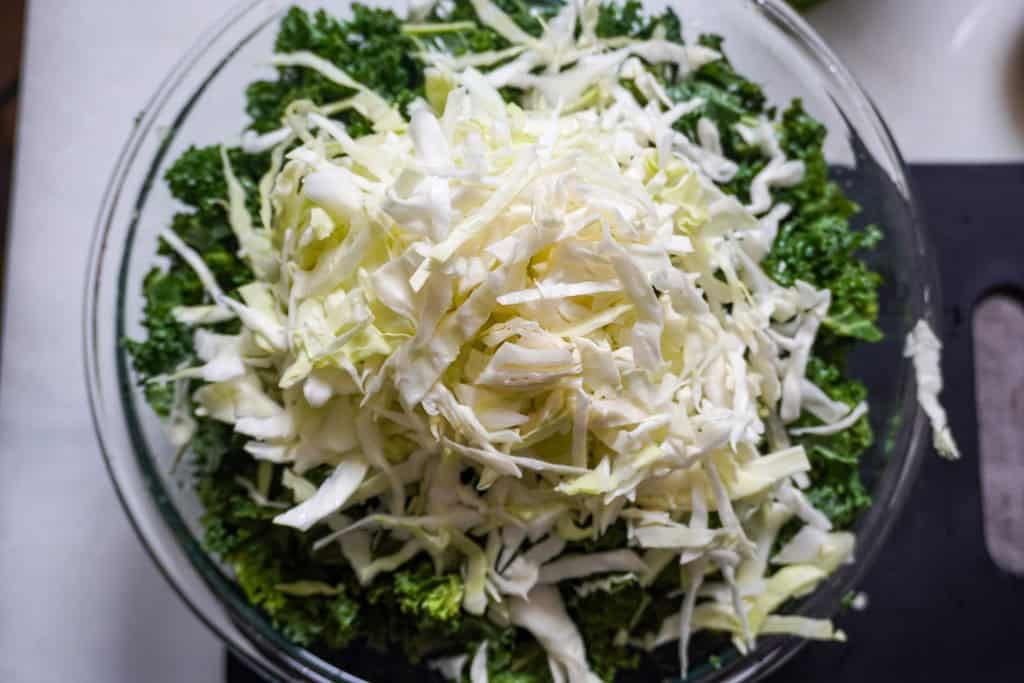 cabbage on a kale salad in a clear bowl