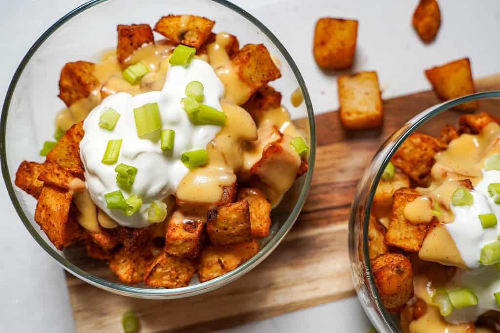 cheesy fiesta potatoes in a bowl with sour cream and green onions