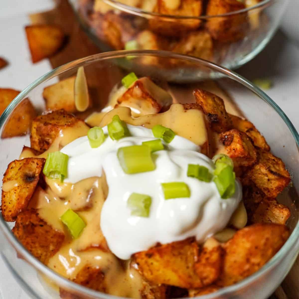 cheesy fiesta potatoes in a bowl with sour cream and green onions