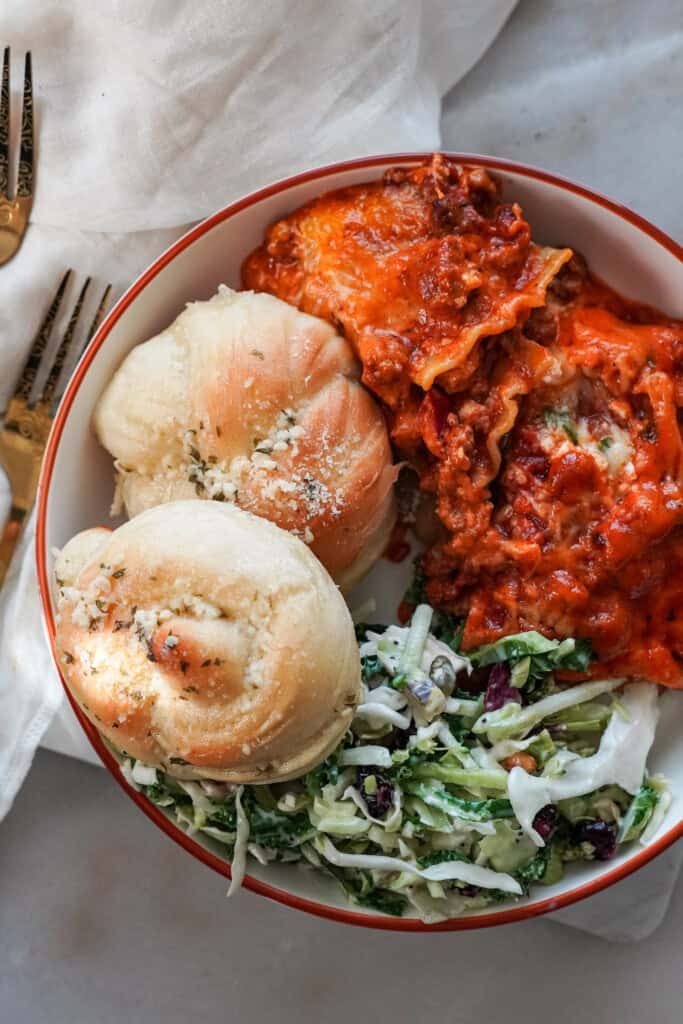 garlic knots on a plate with pasta and salad