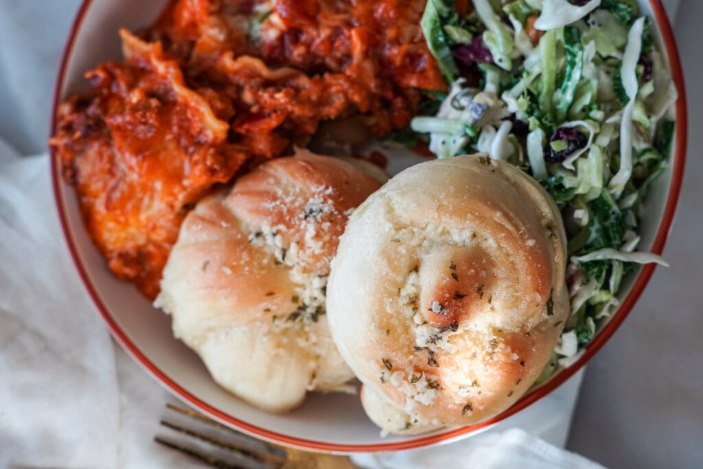 garlic knots on a plate with pasta and salad