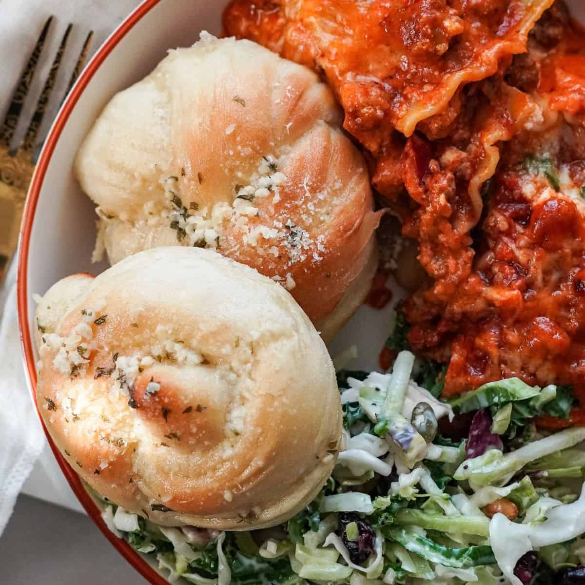 garlic knots on a plate with pasta and salad