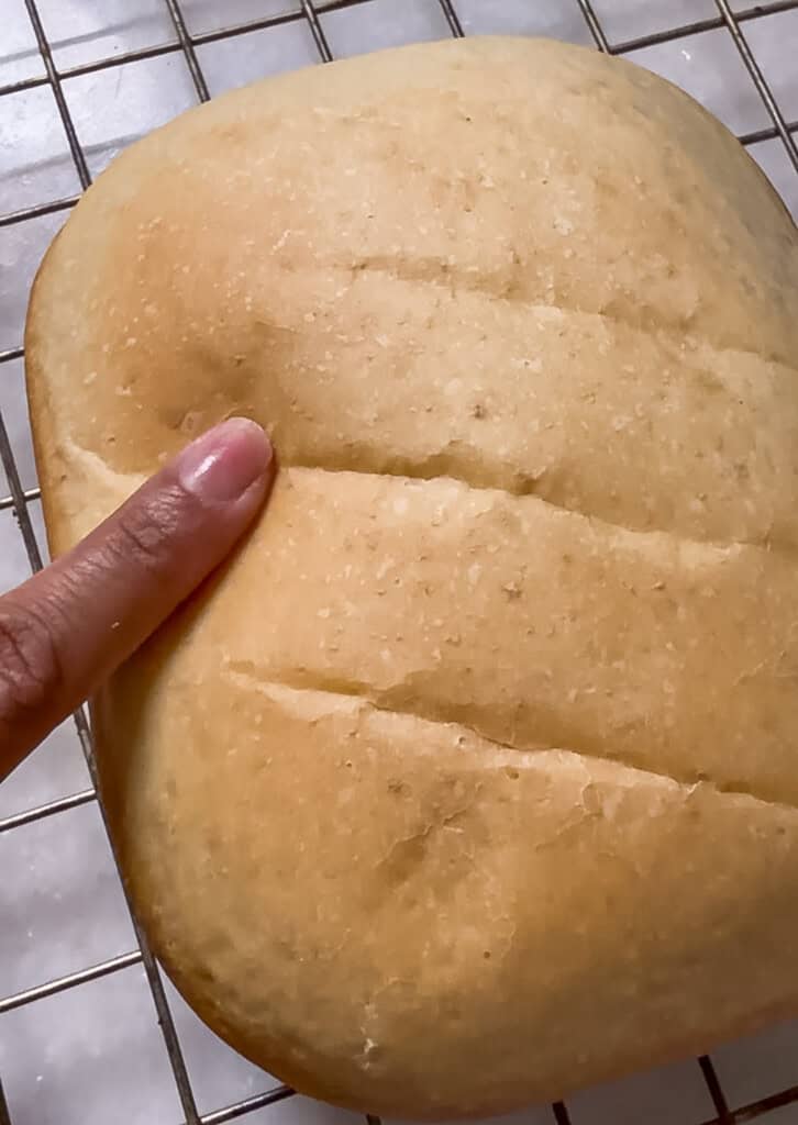 pressing a loaf of bread to show how soft it is